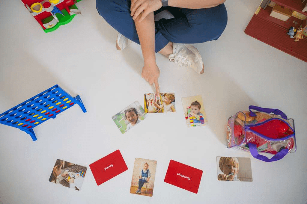 Play-based pediatric speech therapy materials, flashcards, and toys arranged on the floor